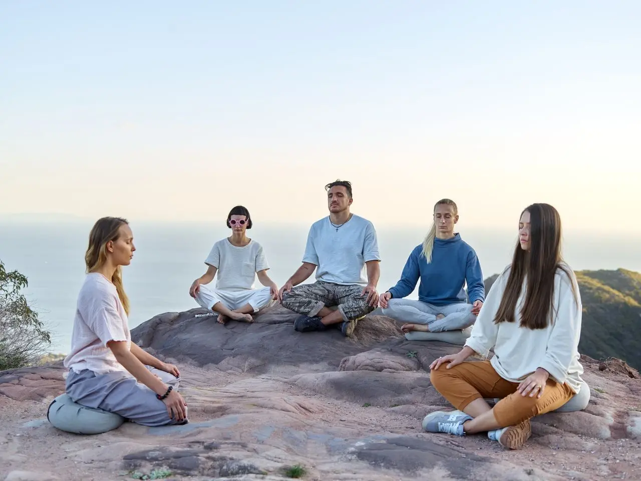 Grup halinde meditasyon Deniz kenarındaki kayalıkta bağdaş kurup meditasyon yapan bir grup insan
