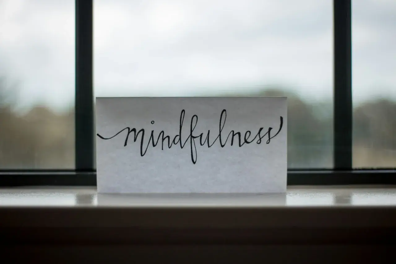 Mindfulness egzersizleri rehberi Pencere kenarında duran kâğıt üzerinde el yazısıyla yazılmış mindfulness kelimesi
